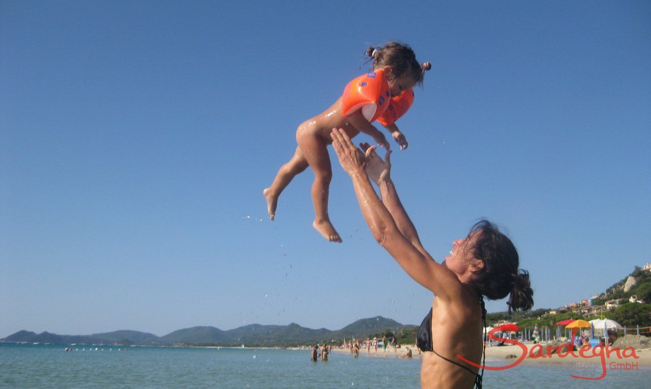 Madre fa volare la sua bambina in aria, al mare di Monte Nai