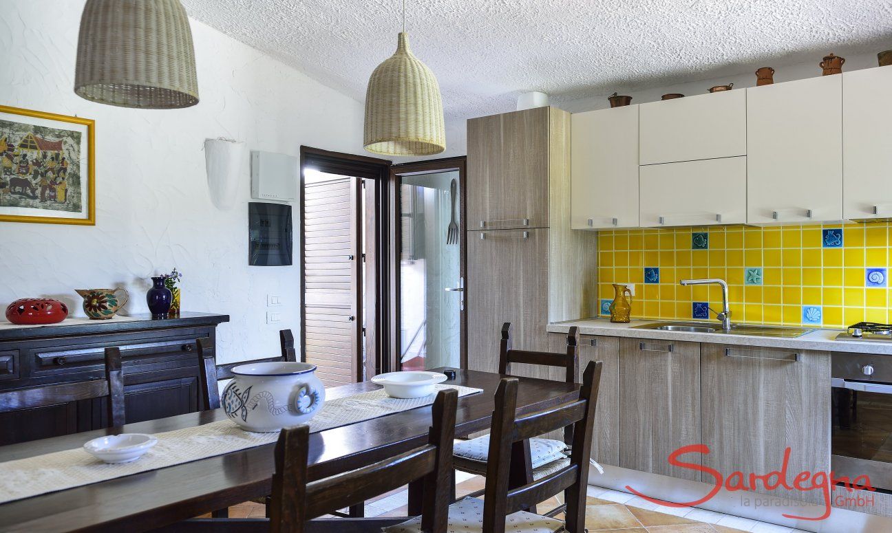 Villa Gaia | Cucina abitabile con tavolo rustico e porta al giardino cucina