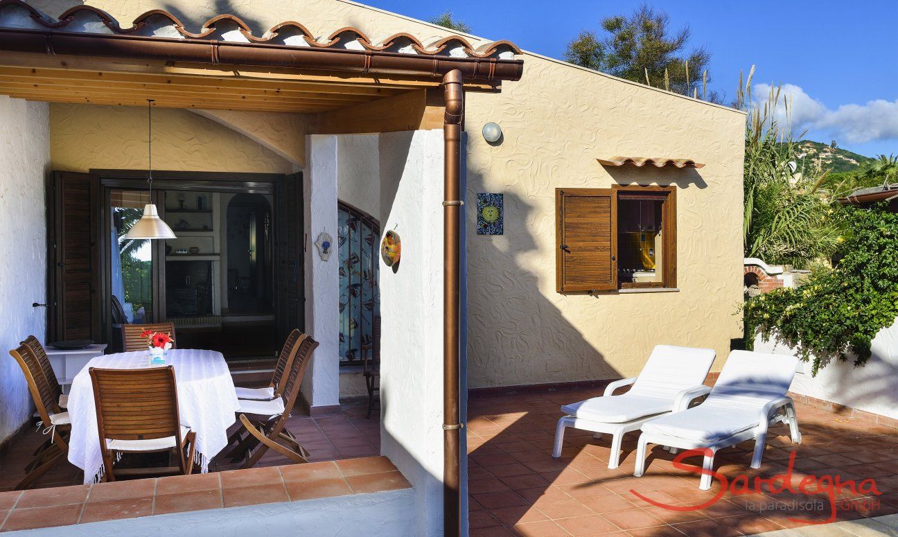 Villa Gaia | Ingressa alla casa attraverso la veranda con tavolo da pranzo e lettini da sole Villa Gaia