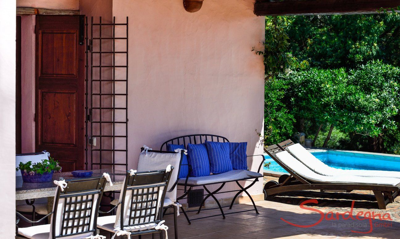 Veranda con tavolo, panca e lettini a bordo piscina