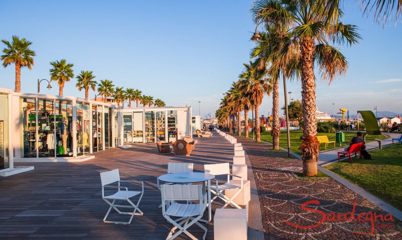 Passeggiata di Golfo Aranci in mezzo a due file die palme con eleganti negozi e bar