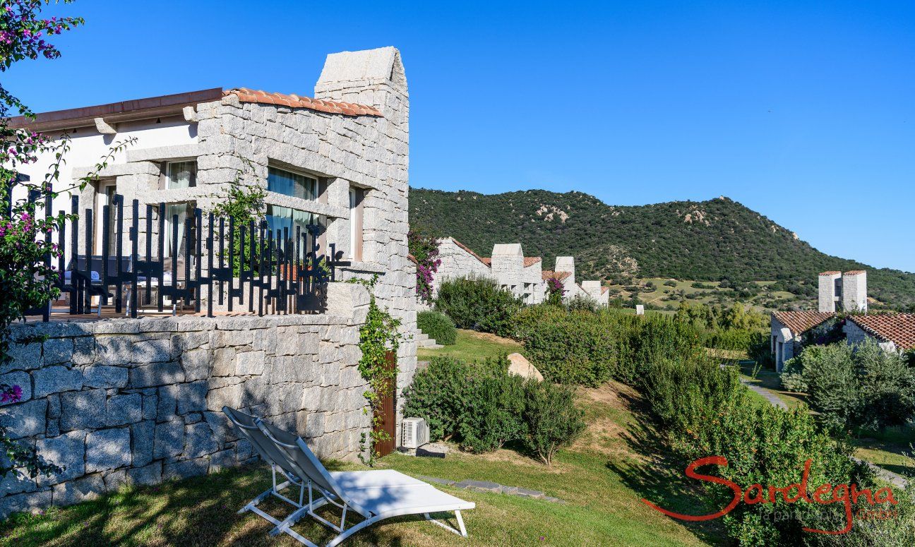 Casa in granito e giardino con lettini da sole