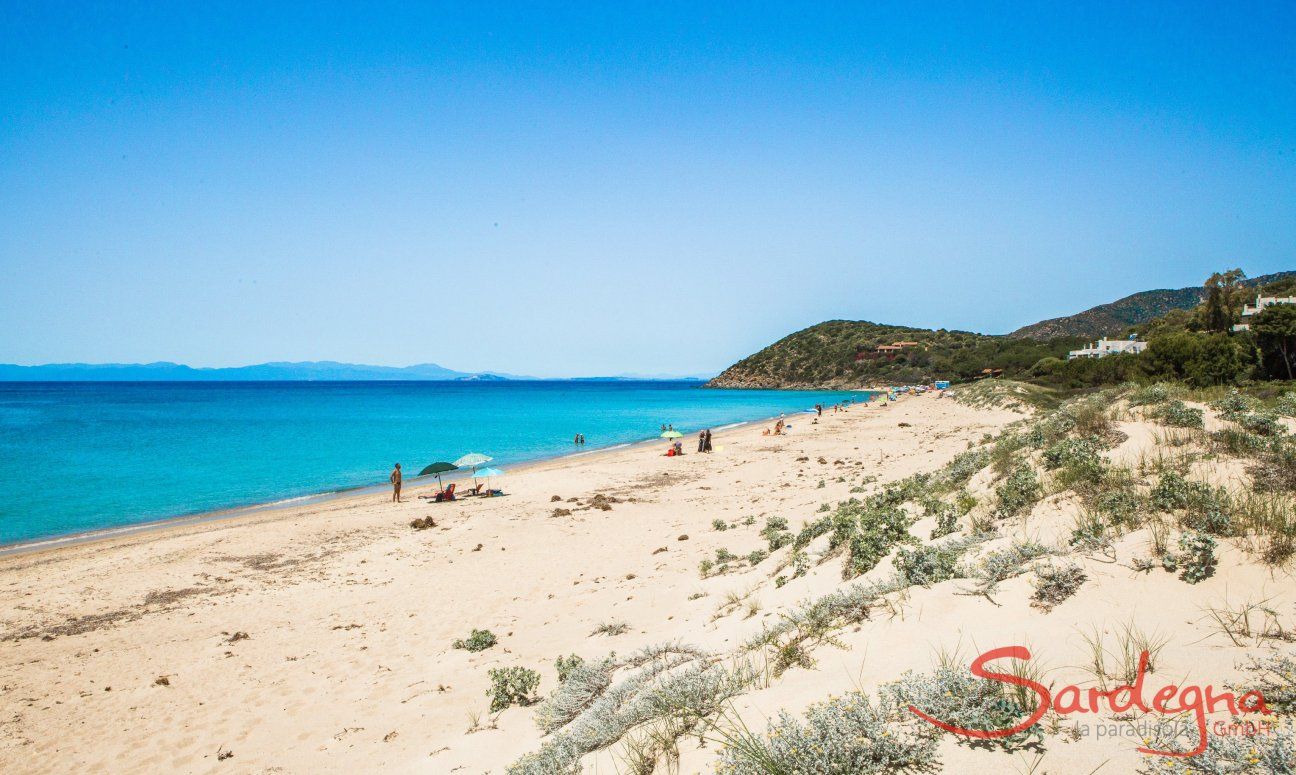 Spiaggia larga e bianca di Geremeas con mare blu e la costa di Cagliari