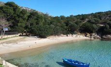 Peschereggio tradizionale sospeso nell'acqua trasparente di Cala Moresca, Golfo Aranci