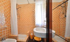 Bagno con piastrelle arancione con doccia di  Villa Serena, Costa Rei