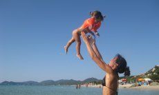 Madre fa volare la sua bambina in aria, al mare di Monte Nai