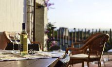 Li Conchi 7 | Aperitivo in veranda Bottiglia di vino bianco con due bicchieri sulla veranda di Li Conchi 7 con vista mare