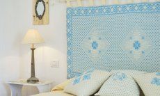 Li Conchi 7 | Camera 1 con letto matrimoniale con testata in tessuto sardo Letto matrimoniale con tavolino, lampada e testata in stile sardo in Li Conchi 7