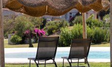 Lettini da sole sotto un ombrellone a fianco alla piscina di Li Conchi