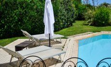 Villa del Campo | Lettini e ombrellone alla piscina con viste nel bel giardino verde Pool con lettini da sole