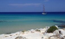 Spiaggia con mare turchese e barca a vela