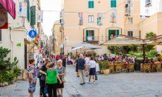 Le stradine e piazze pedonali di Alghero con gente che si incontra e fa shopping