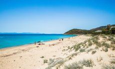 Spiaggia larga e bianca di Geremeas con mare blu e la costa di Cagliari