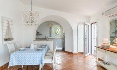 Li Conchi 30 | Tavolo da pranzo e scorcio della cucina e della porta d'ingresso Presentazione Li Conchi 30