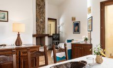 Villa Gioconda 21 | Zona pranzo con tavolo rustico per mangiare e vista verso la zona relax del salotto Interno della casa